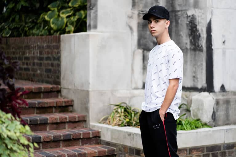 Tommy B wears King Apparel Leyton curved peak cap in black, Manor t-shirt in white and Tennyson tracksuit bottoms in black