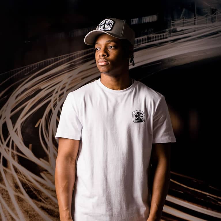 Poundz wears KIng Apparel Regal curved peak cap in stone grey and t-shirt in white