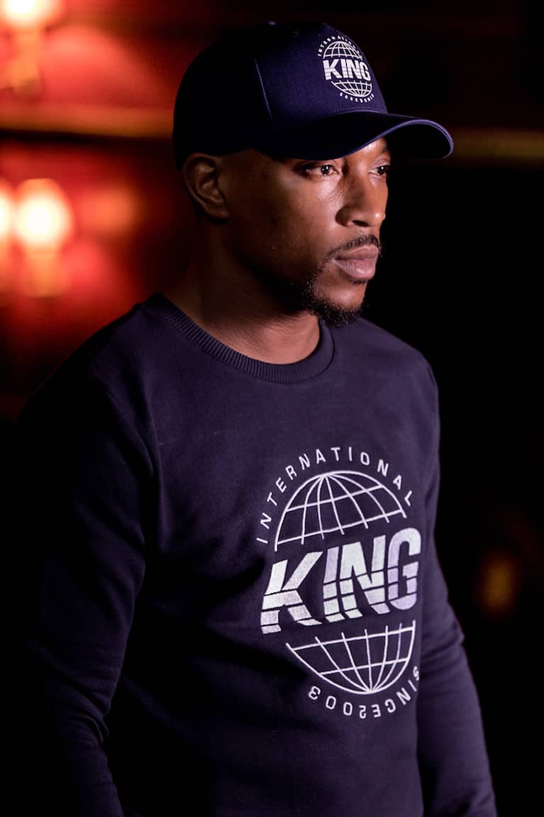 Ashley Walters wears curved peak cap and sweatshirt from King Apparel Autumn / Winter 2018 collection