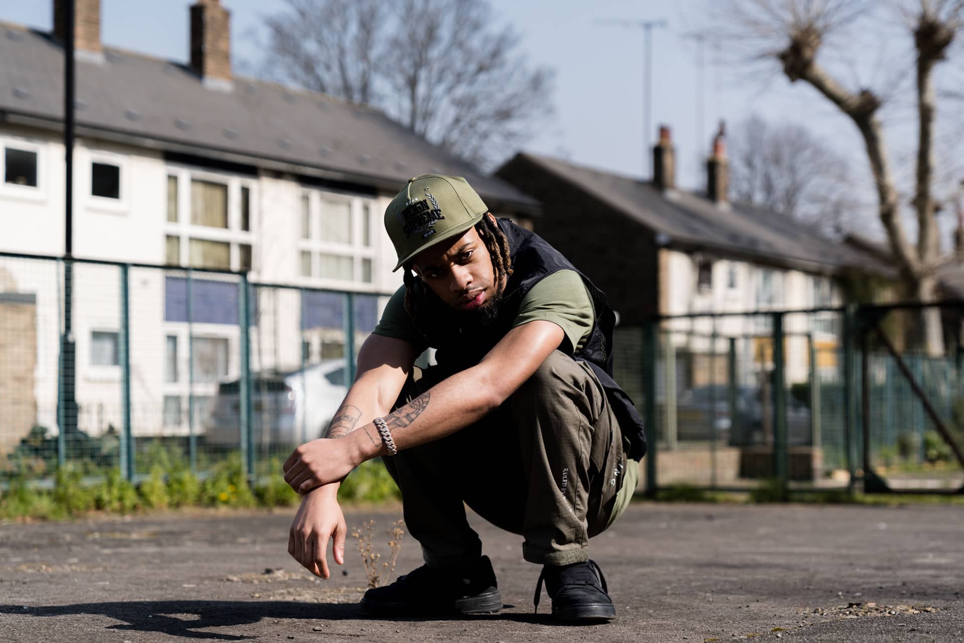 Bandanna wears King Apparel Earlham Tech snapback cap, t-shirt and cargo pants in fern green and tactical vest in black